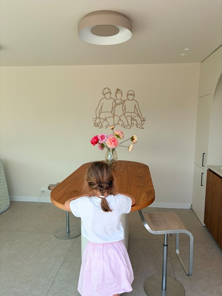 Houten lijnportret van drie kinderen boven de eettafel
