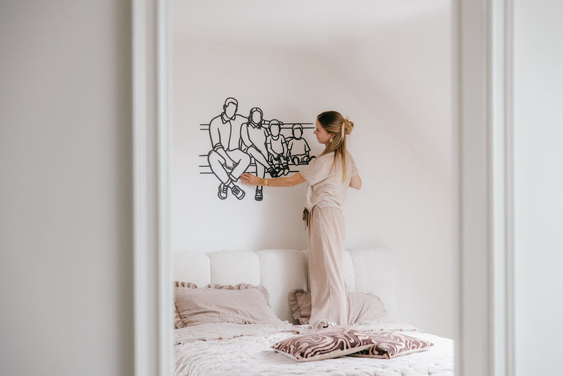 Zwart houten lijnportret van een gezin, opgehangen boven het bed
